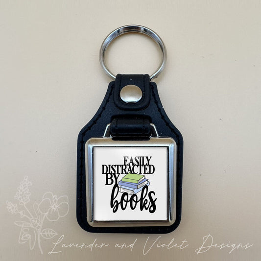 DISTRACTED BOOKS VINYL KEYCHAIN SQUARE
