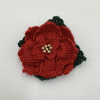 Red petals, dark green leaves and gold tone beaded center
