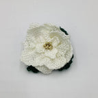 White petals, dark green leaves, gold tone beaded center