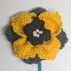 yellow flower with black center, white french knots and heathered green leaves