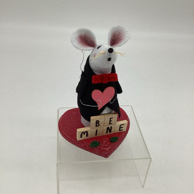 Light gray mouse holding pink heart on red base