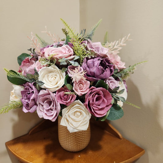 Roses and peonies in purples, mauve and cream with a peach colored glass vase